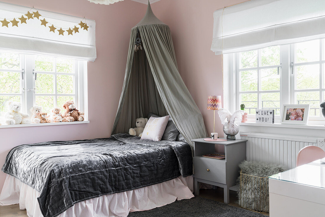 Bed with velvet bedspread and canopy in girl's bedroom with pink walls