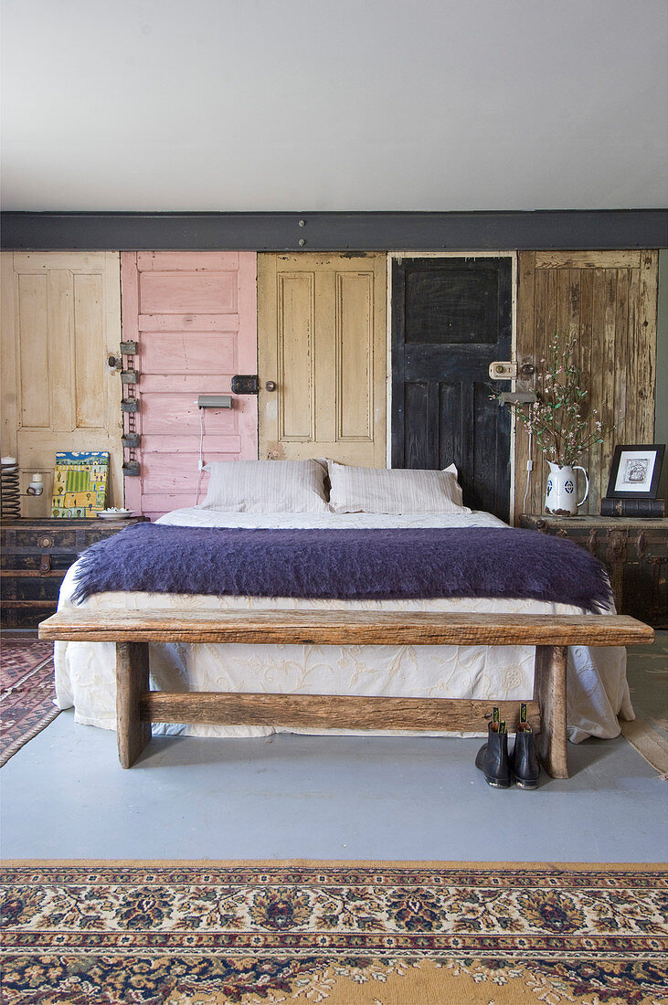 Rustic bedroom bench, double bed and wall panels made from vintage wooden doors in bedroom