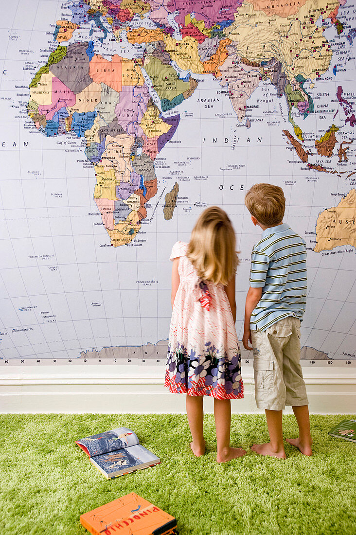 Two children standing in front of map of the world