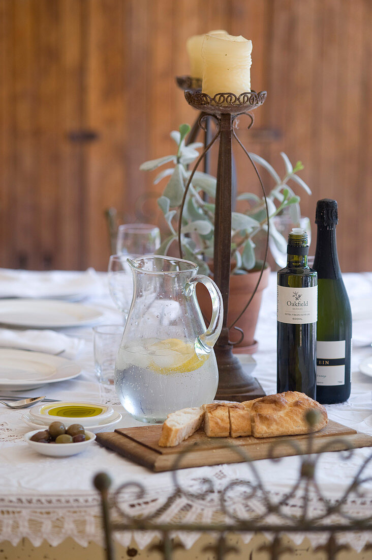 Gedeckter Tisch mit Ciabatta, Oliven, Olivenöl und Wasserkrug