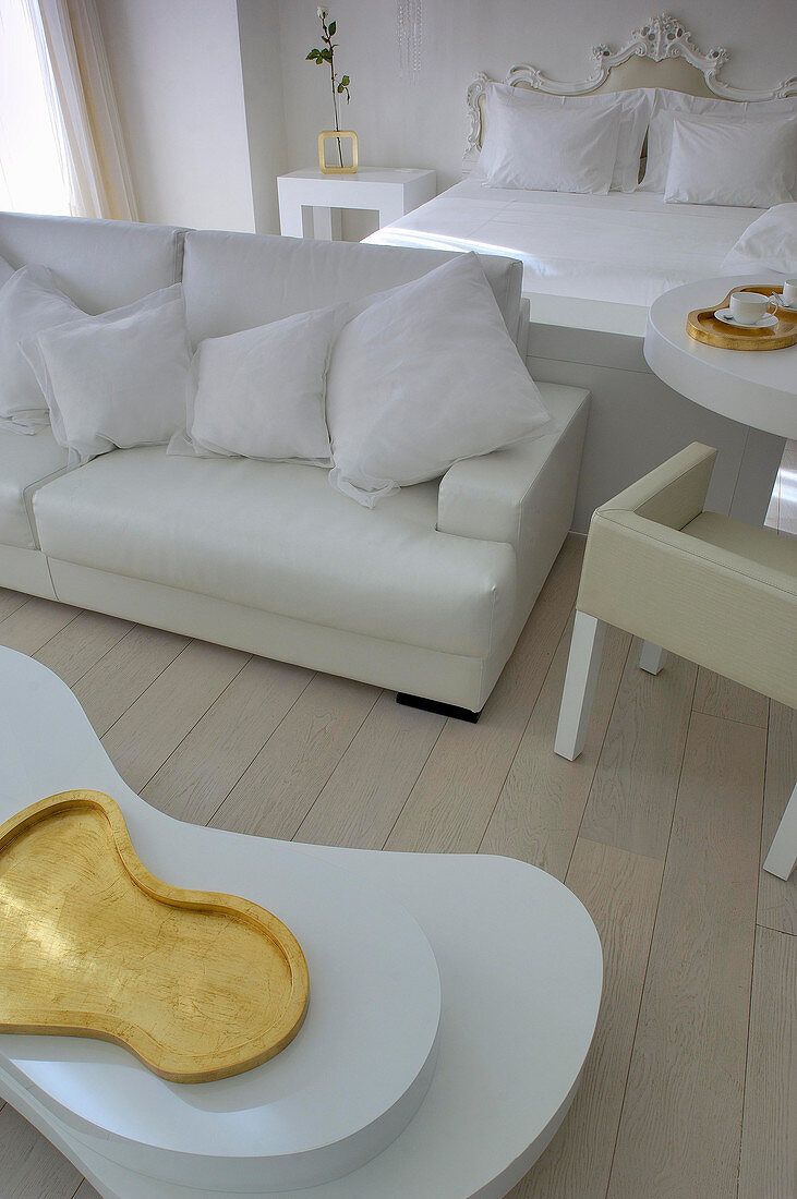 Weißes Zimmer mit Doppelbett, Couch und organisch geformtem Couchtisch