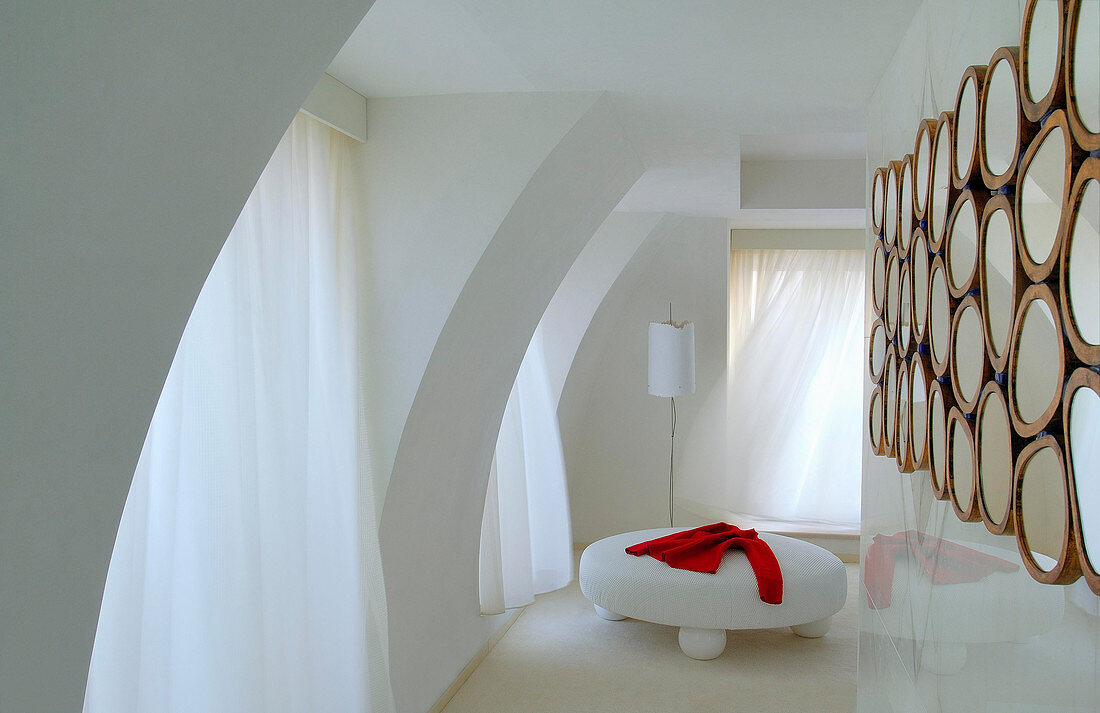 Runder, weißer Polstertisch in elegantem Zimmer mit Raumteiler