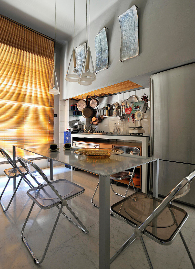 Designer table and plexiglas chairs in open-plan kitchen