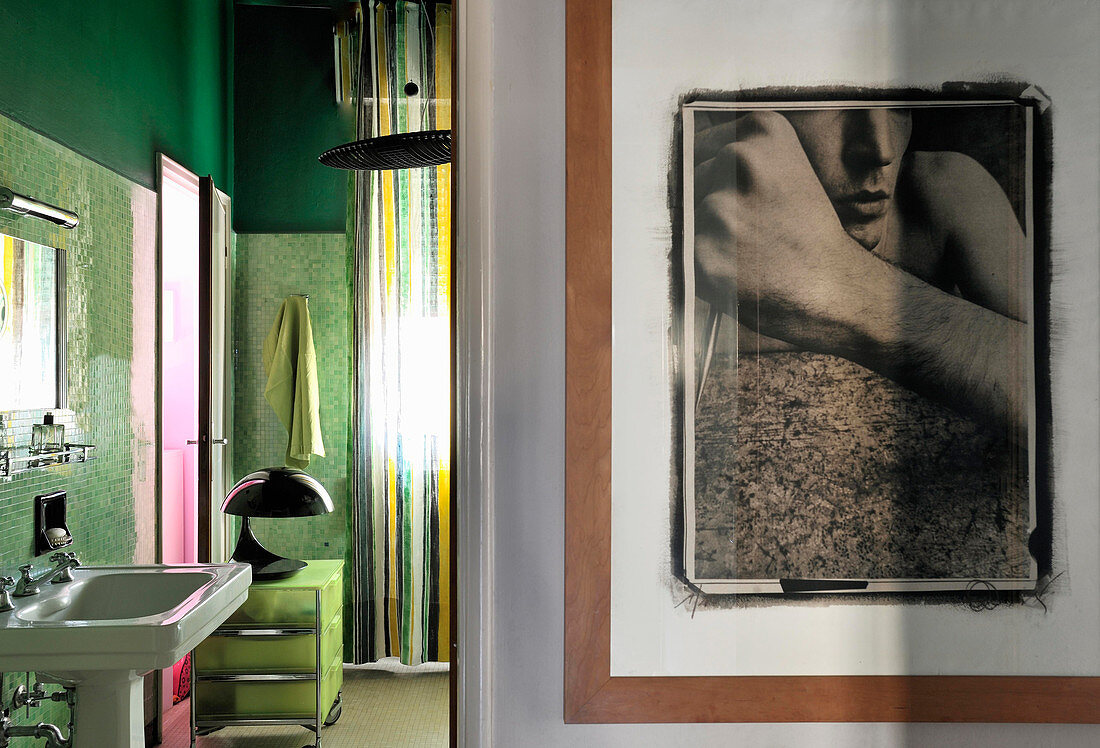 Großformatige Fotografie an der Wand, Blick ins Badezimmer mit grünen Mosaikfliesen
