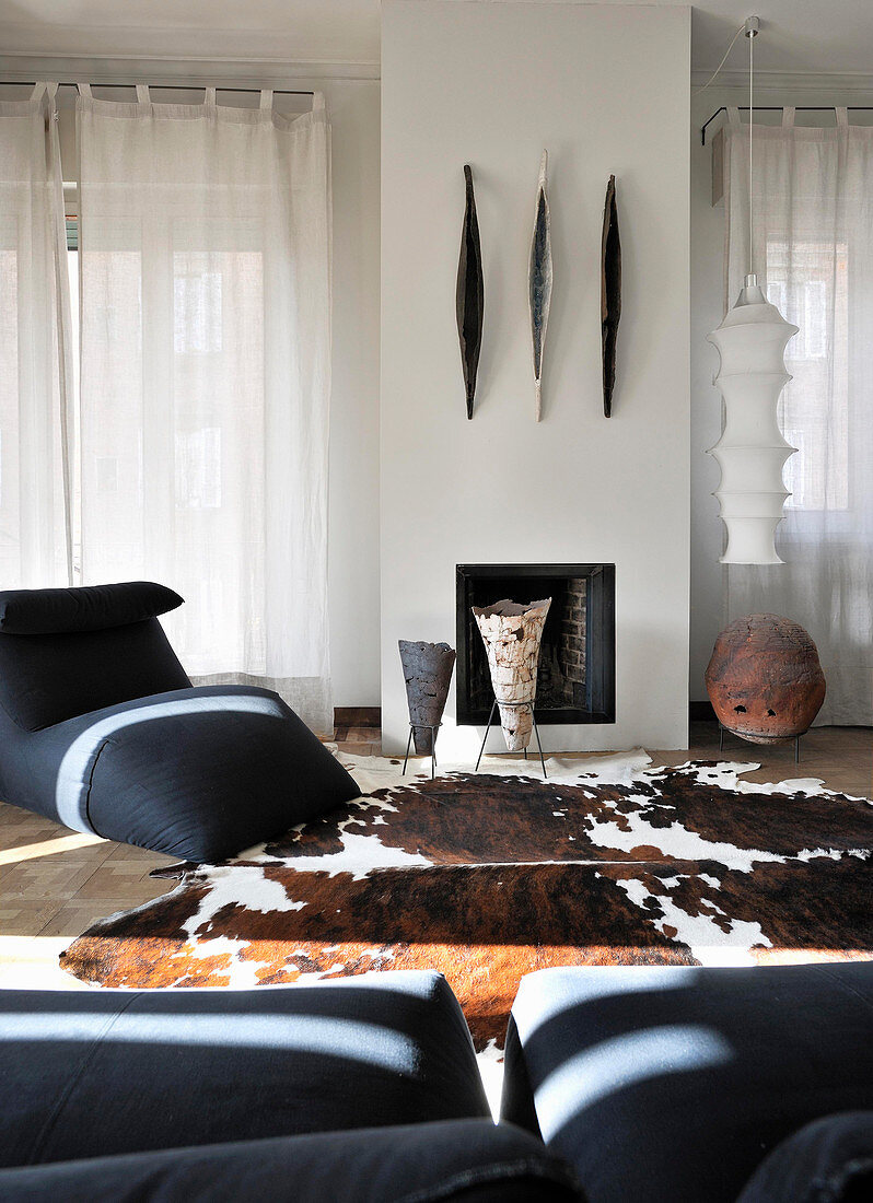 Designer armchairs and cowhide rug in front of fireplace in living room