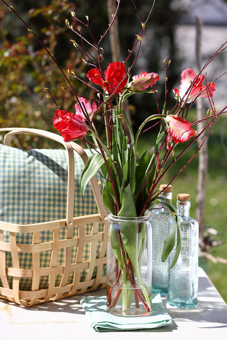 Strauß mit Tulpen und Zweigen auf dem Gartentisch