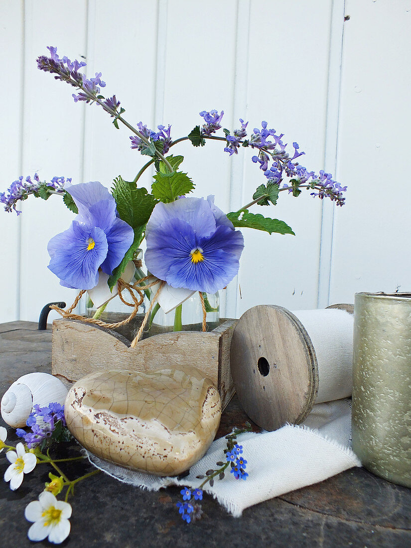 Frühlingsdekoration aus blauen Stiefmütterchen und Pfefferminzblüten