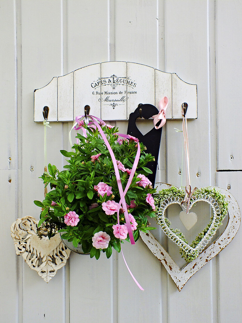 Heart ornament and pink mini petunias on wooden wall