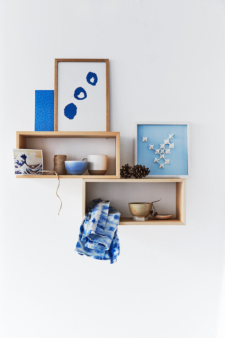 Bowls and handmade pictures in blue and white on wooden shelves