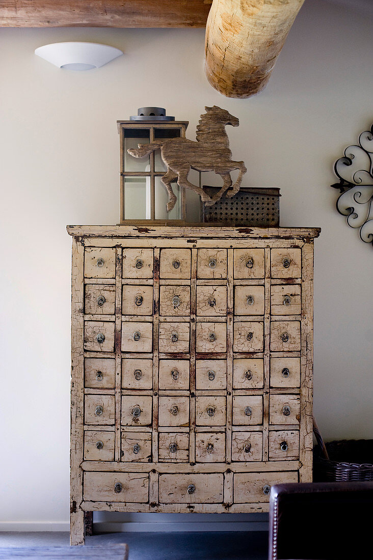 Lantern and horse sculpture on top of vintage apothecary cabinet