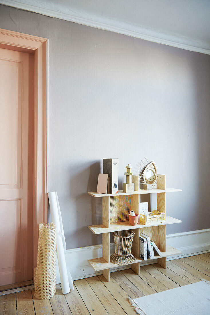 Pale wooden shelves with woven wall panels in period interior