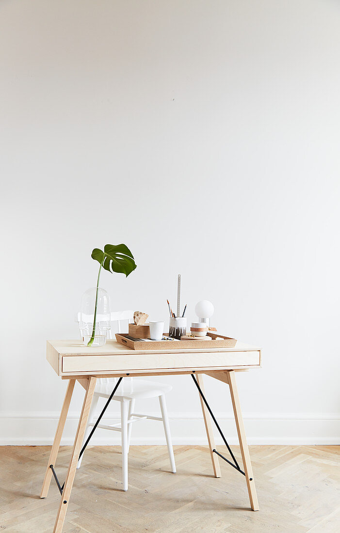 Schreibtisch aus hellem Holz, Tablett mit Bürobedarf und Monsterablatt