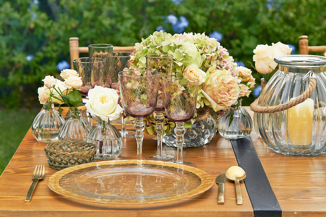 Festlich gedeckter Tisch mit Platztellern, Hortensien, Rosen und Windlichtern