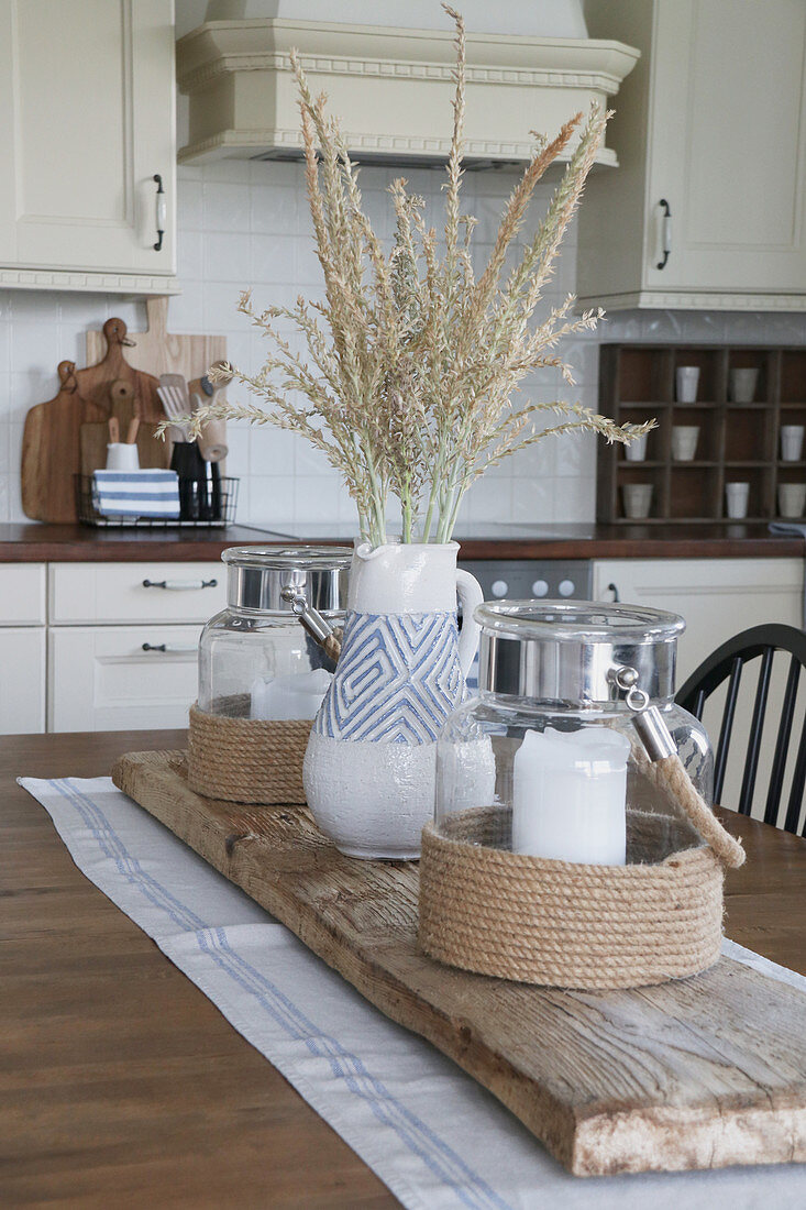Sommerlich dekorierter Küchentisch mit Laternen und blau-weißer Tonvase auf Schwemmholzbrett