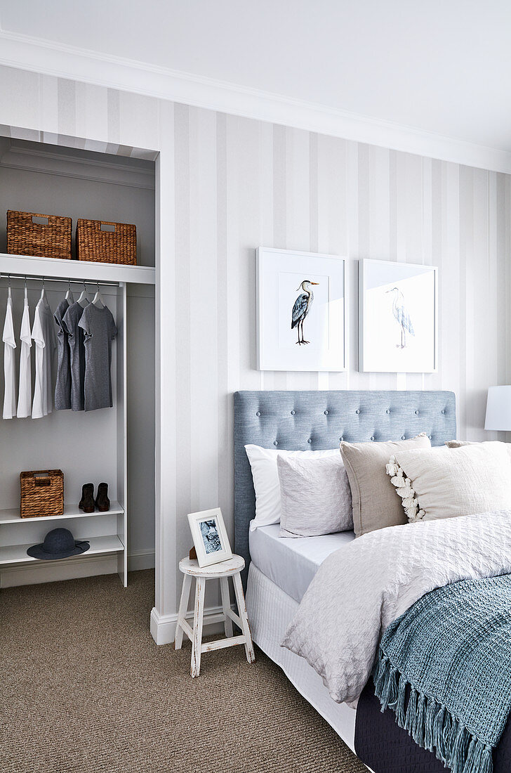 Doppelbett mit Bettkopfteil in hellem Schlafzimmer mit Tapete, Blick in begehbare Garderobe