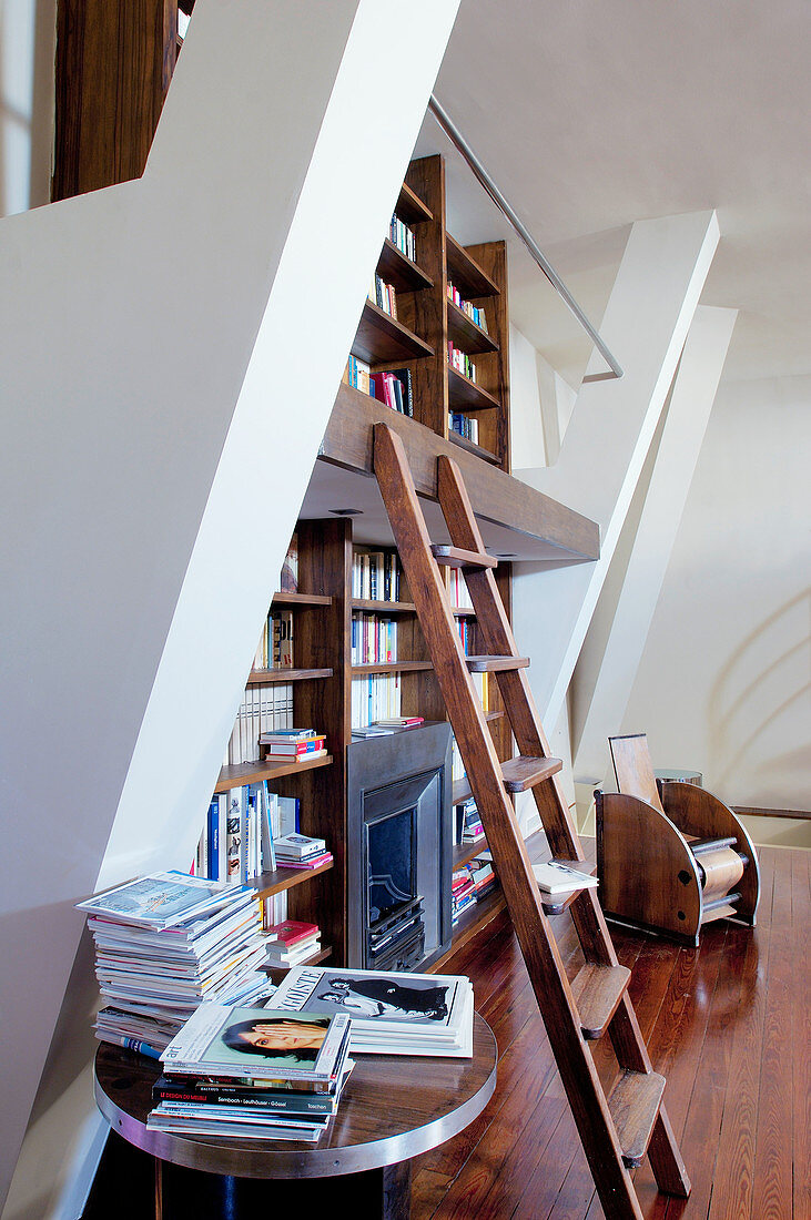 Bücherwand mit Bibliotheksleiter und Kamin in hohem Raum