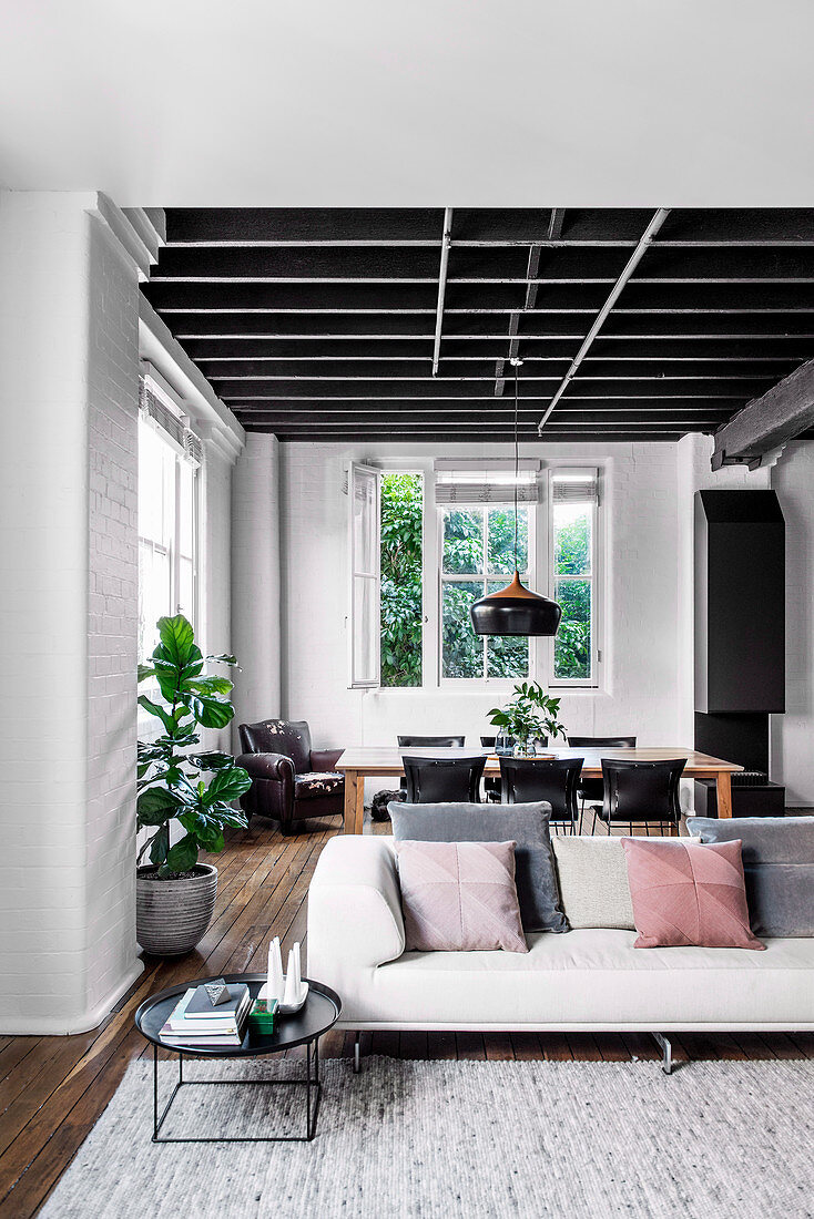 Open living room in grey tones with sofa and dining table in a loft