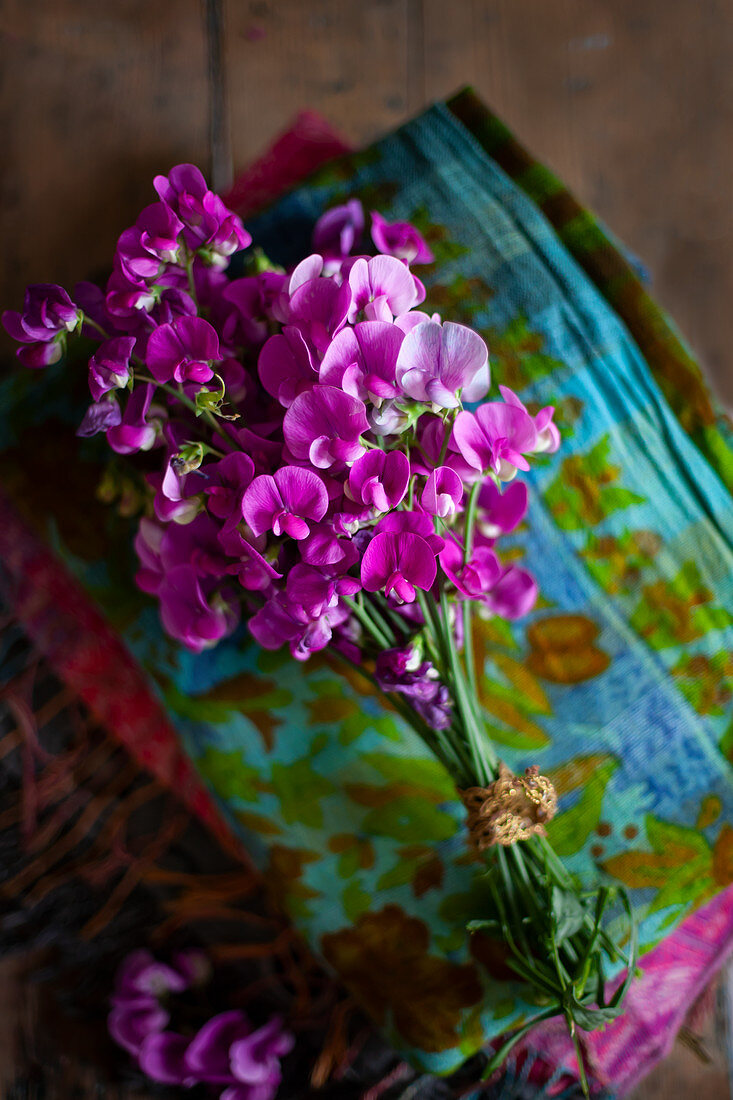 Bouquet of pink sweet peas on stack of folded fabrics