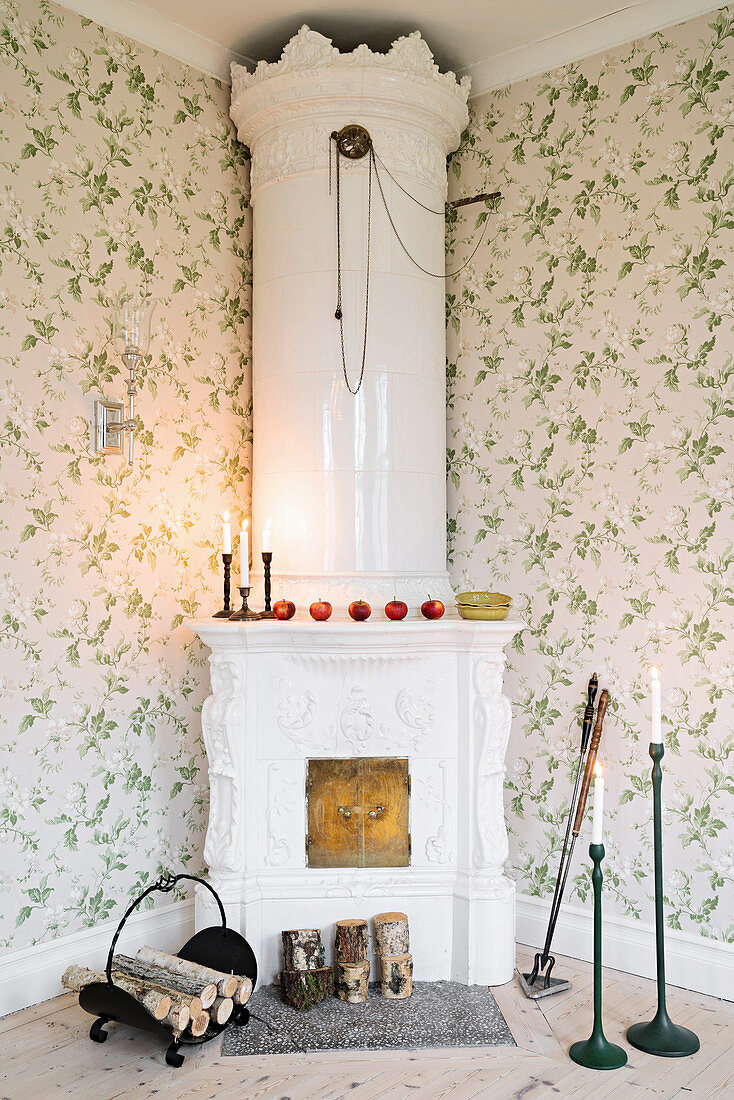 Antique, white stove in corner of living room with floral wallpaper