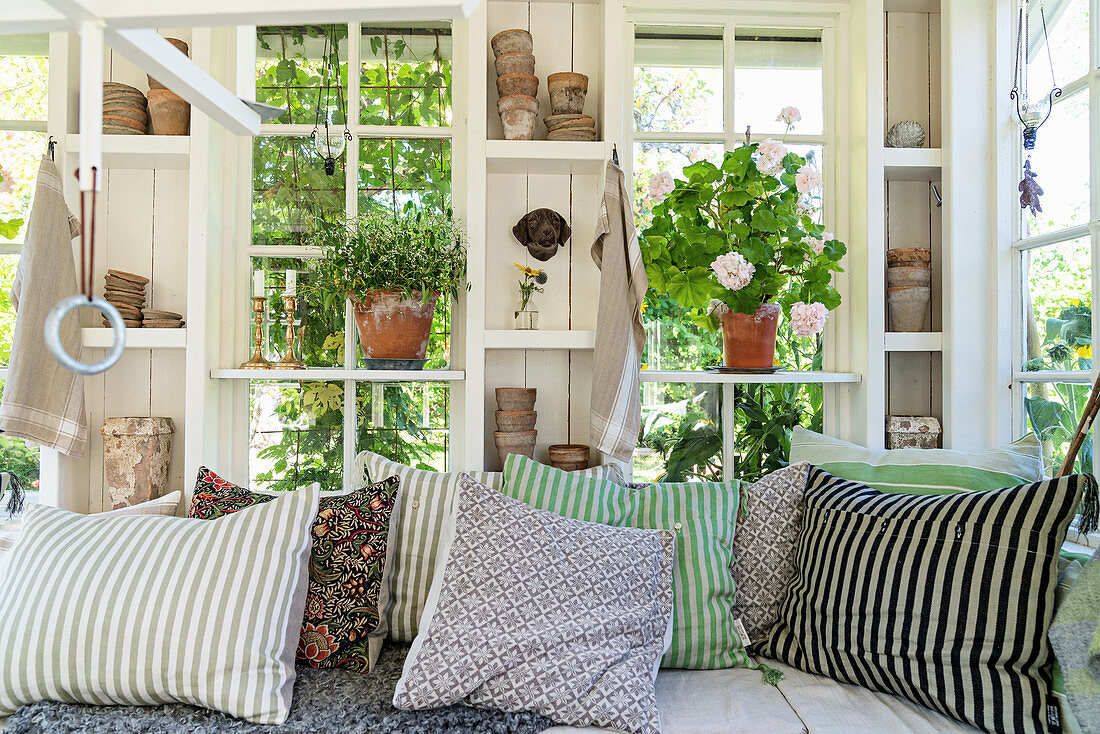 Scatter cushions with various patterns on bench in summerhouse