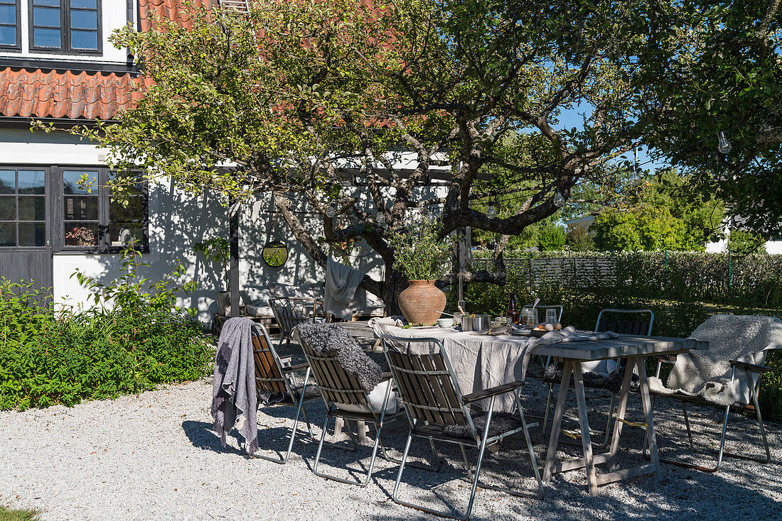 Gedeckter Gartentisch auf der Terrasse mit Kies im Sommergarten