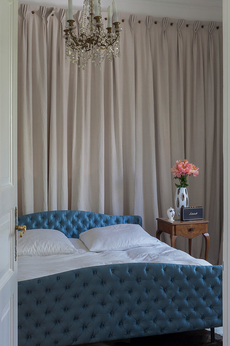 Blau gepolstertes Bett im Schlafzimmer mit Stoffbehang