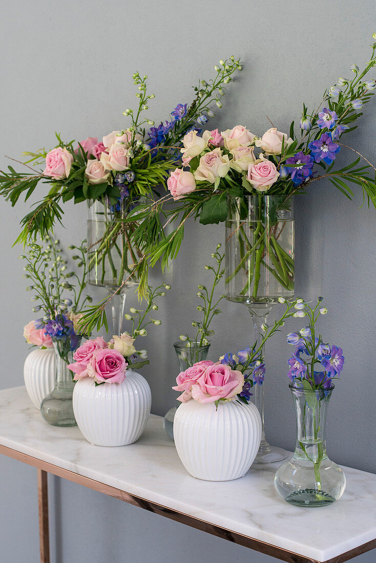 Roses and delphiniums in various vases