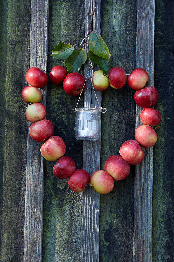 Heart-shaped wreath of apples with candle lantern