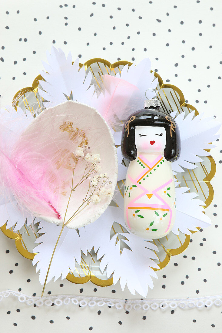 Geisha figurine on paper flower on plate with other decorations