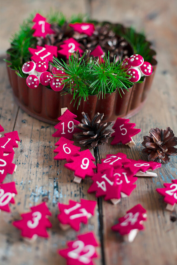 Numbered Christmas trees made from red felt and conifer twigs in flan tin