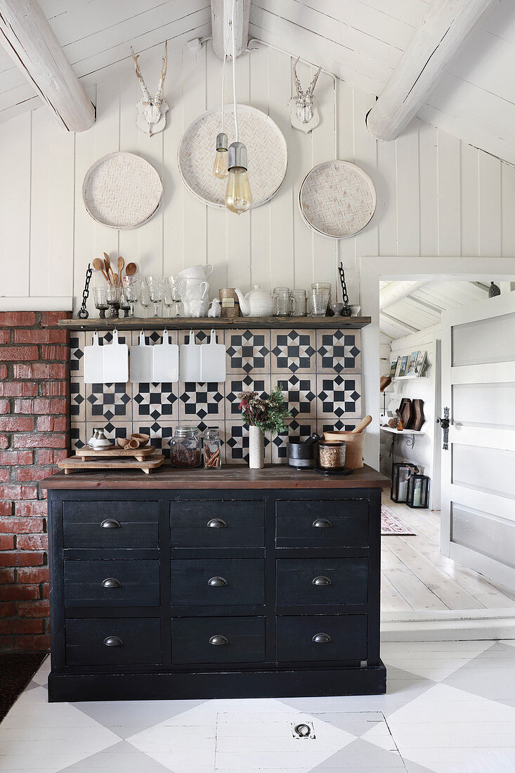 Black chest of drawers in rustic kitchen with chequered floor