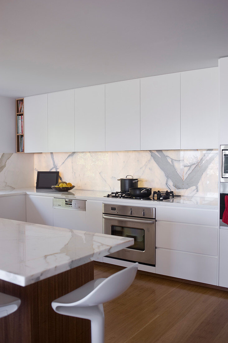 Elegant, white fitted kitchen with marble elements