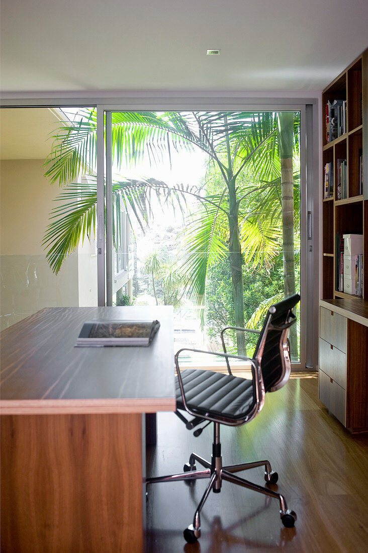Desk and swivel chair in study with glass sliding wall