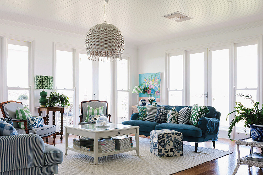 Light-flooded living room with blue upholstered sofa and blue and white striped armchairs