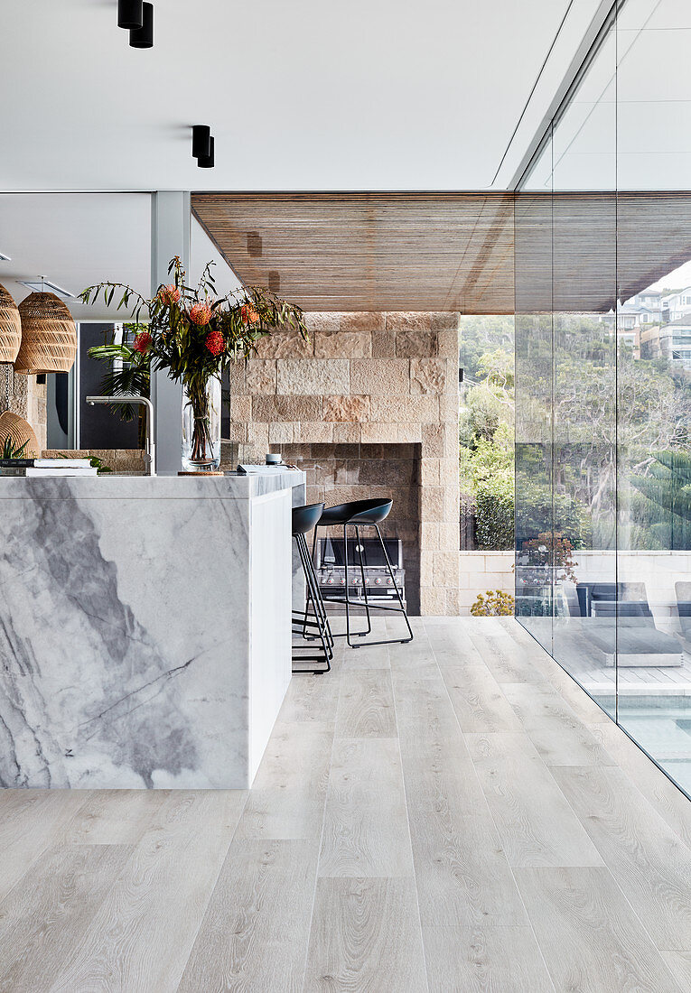 Kücheninsel aus Marmor in offener Küche mit Holzboden und Glasfront