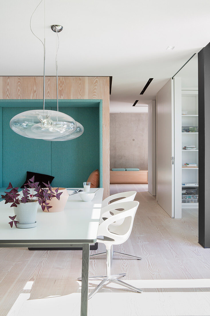 Dining table in front of upholstered niche in wall in modern, architect-designed house