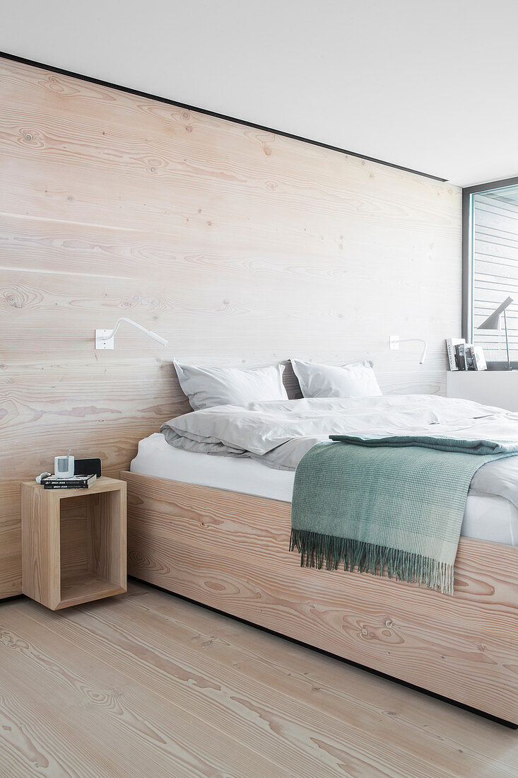 Bett im Schlafzimmer mit hellem Holz an Boden und Wand