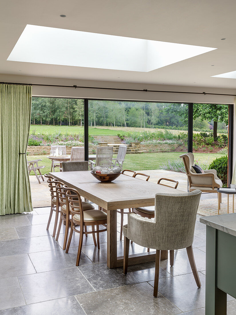 Dining table in bright interior with skylight and wide, glass sliding doors leading to terrace