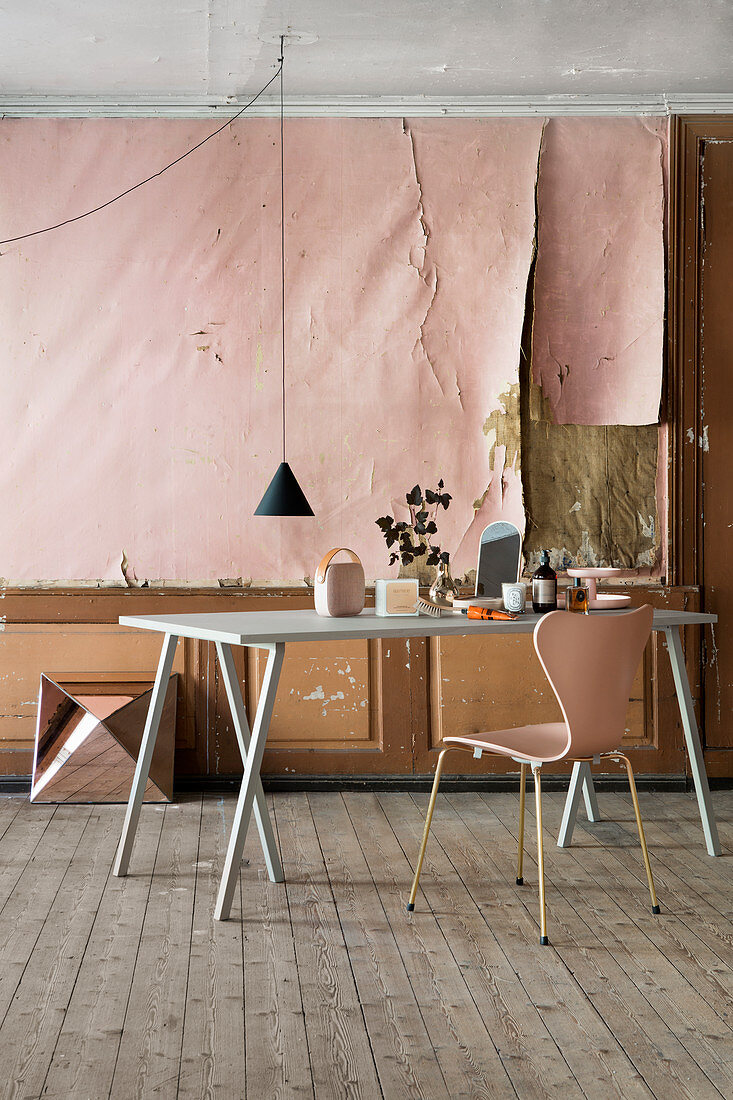 Tisch und Stuhl im Altbau mit abgelöster rosa Tapete