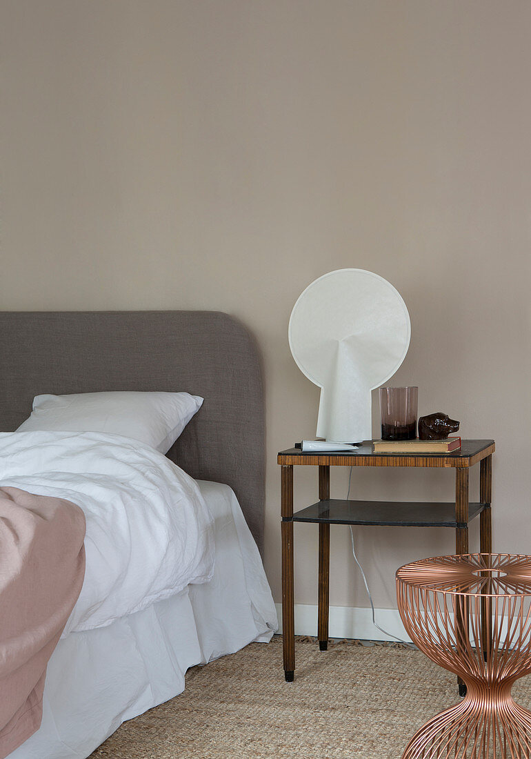Modern lamp on old bedside table in bedroom in nude shades