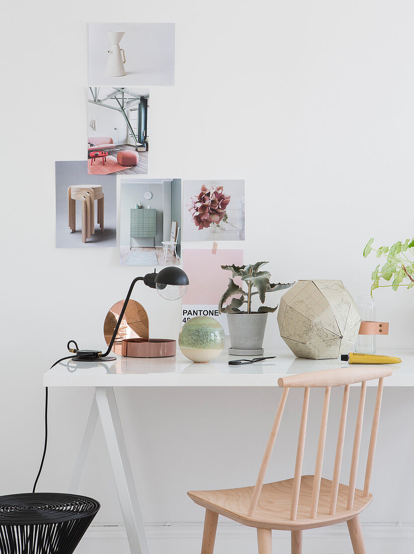Sprossenstuhl am Schreibtisch vor weißer Wand mit Collage