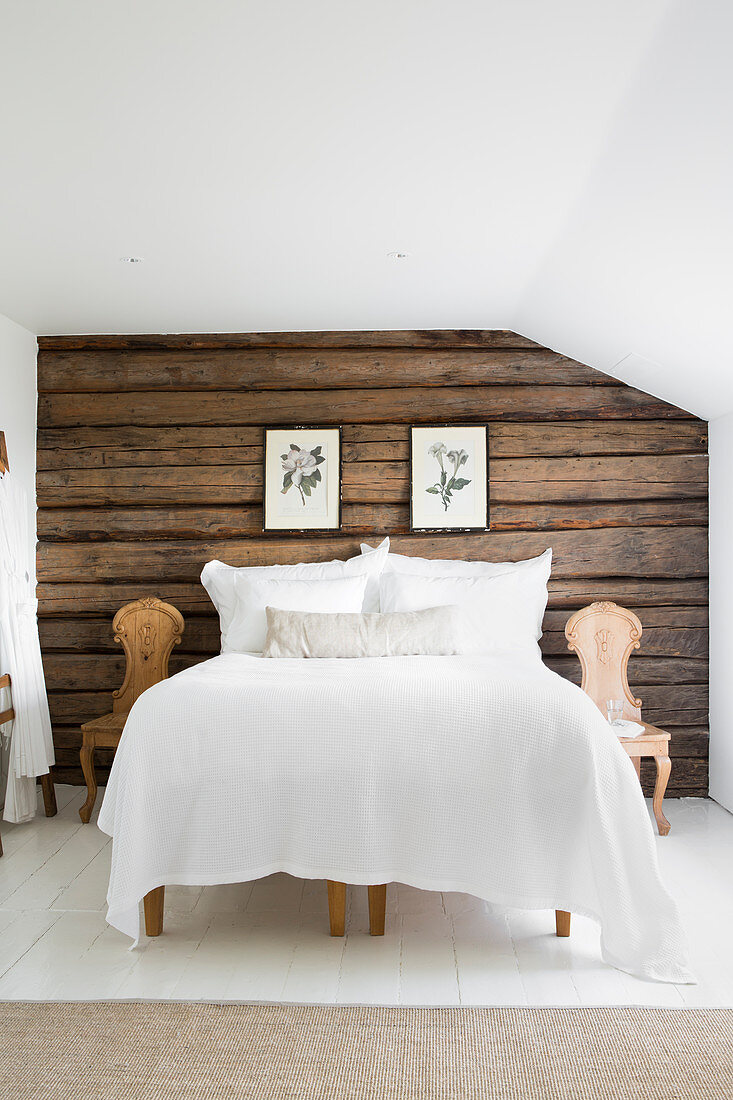 Schlafzimmer im Landhausstil mit rustikaler Holzwand hinterm Bett