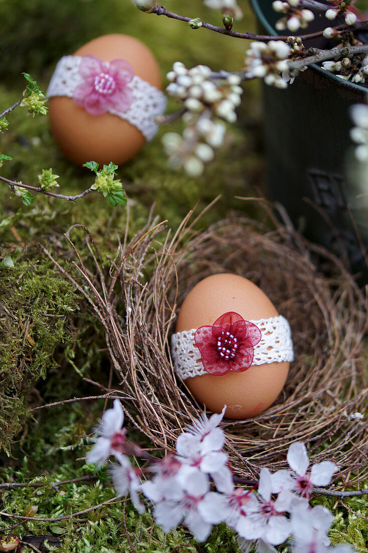 Egg with lace ribbon and cherry plum blossom in Easter nest