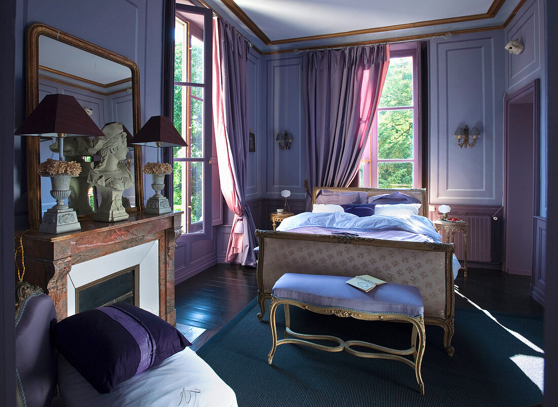 Antique furniture and fireplace in purple bedroom