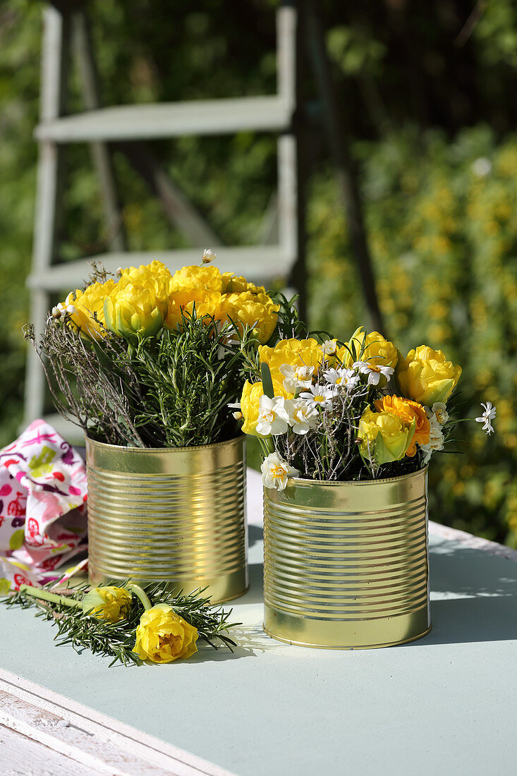 Gelbe gefüllte Tulpen in goldenen Konservendosen als Vasen