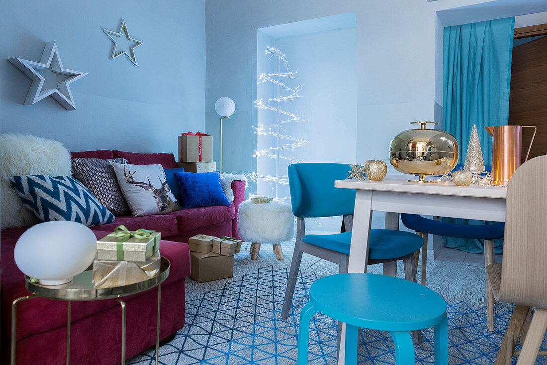 Dining table and red sofa in blue interior decorated for Christmas