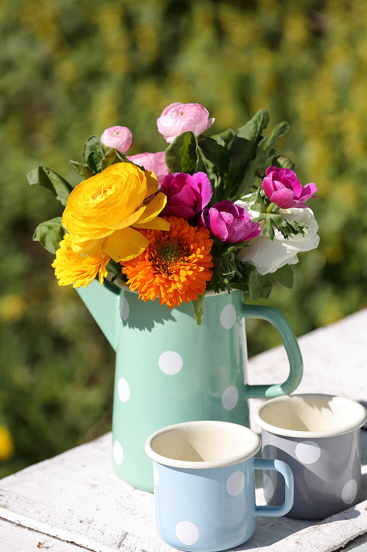 Gerbera daisies, ranunculus and anemones in pastel jug with polka-dot pattern