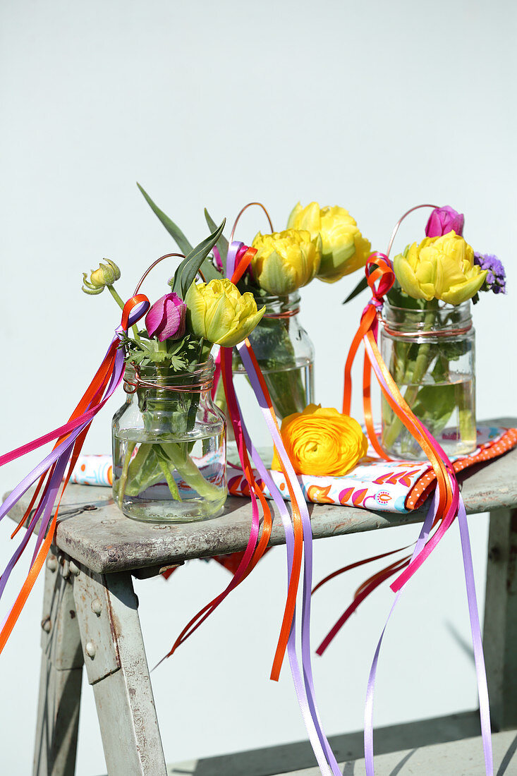 Gefüllte Tulpen in Schraubgläsern mit bunten Stoffbändern