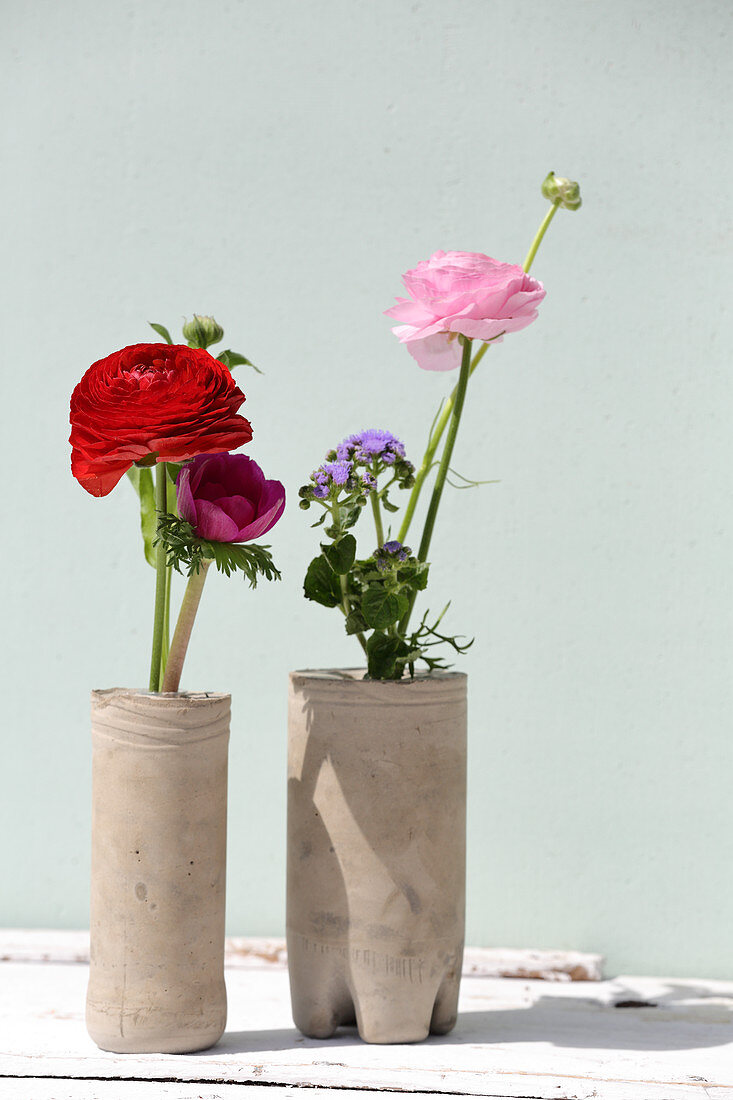 Ranunculus, floss flower and anemones in handmade concrete vases