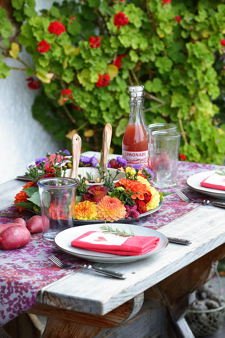 Spätsommerlich gedeckter Tisch mit Blumenkranz auf der Terrasse